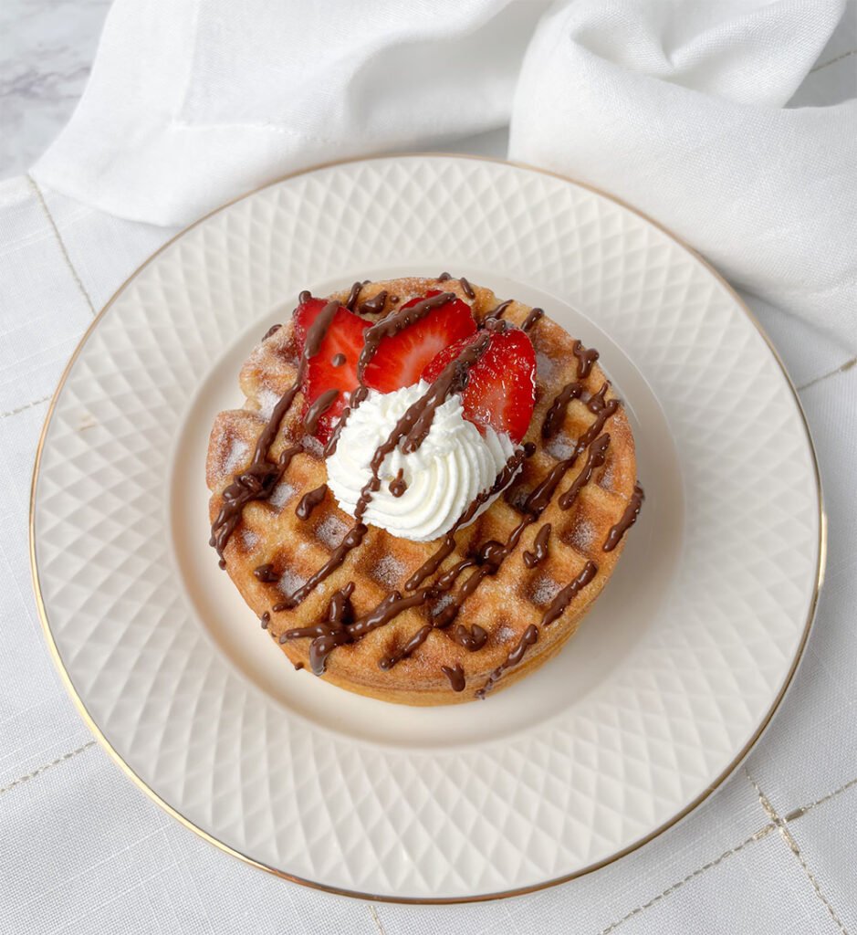 Visão frontal do waffle sem glúten com chantilly, chocolate e morangos